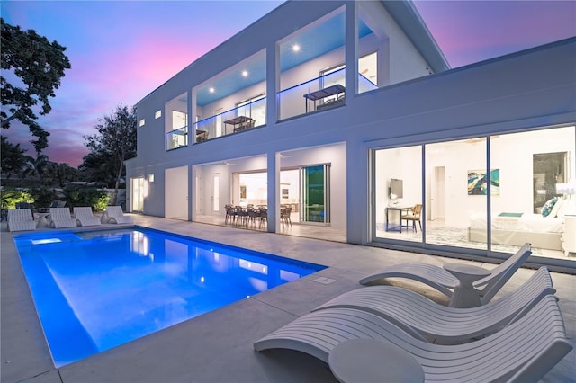 pool at dusk featuring a patio area