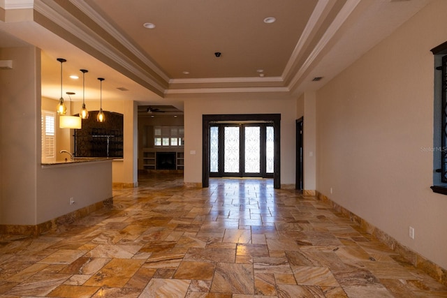 entryway with ceiling fan, a raised ceiling, french doors, and ornamental molding