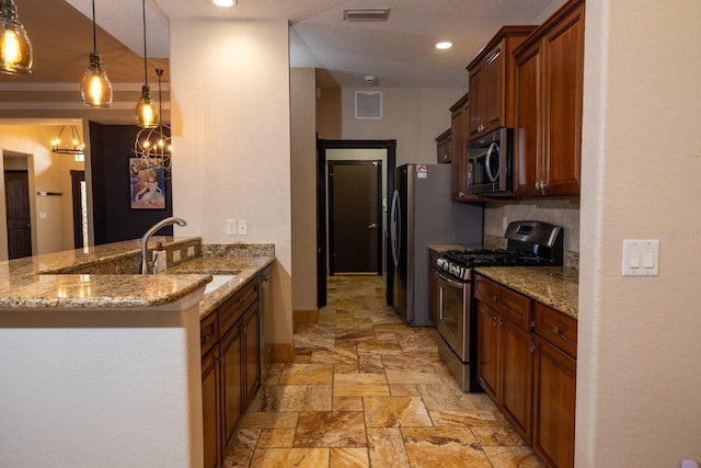 kitchen featuring sink, kitchen peninsula, light stone counters, appliances with stainless steel finishes, and pendant lighting