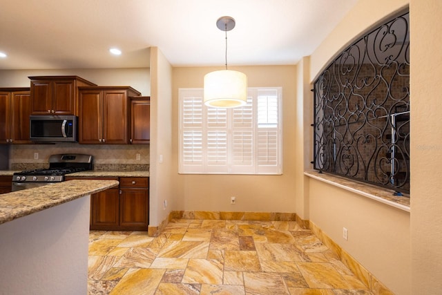 kitchen featuring stainless steel appliances, hanging light fixtures, and light stone counters