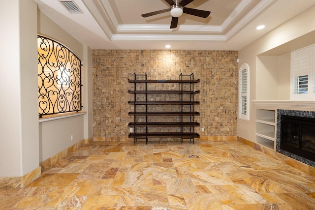 basement with ornamental molding, built in features, ceiling fan, and a tile fireplace