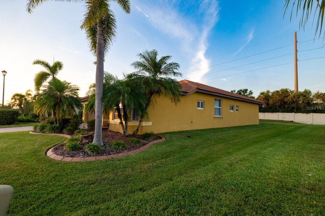 property exterior at dusk featuring a lawn