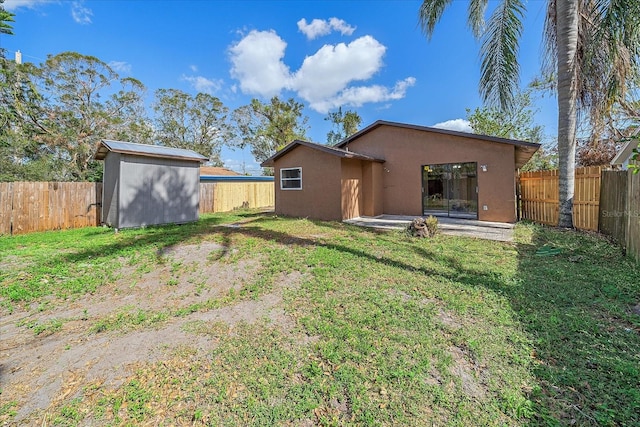 rear view of house with a yard, a patio area, and a storage unit