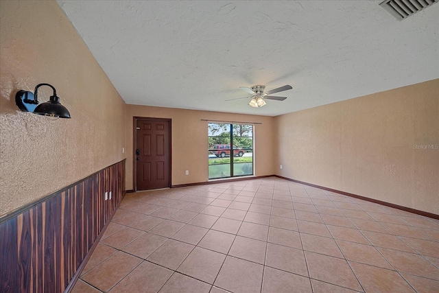 empty room featuring ceiling fan, a textured ceiling, and light tile patterned floors