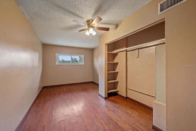 unfurnished bedroom featuring a closet, a textured ceiling, wood-type flooring, and ceiling fan