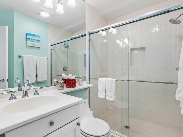 bathroom featuring vanity, a shower with shower door, and toilet