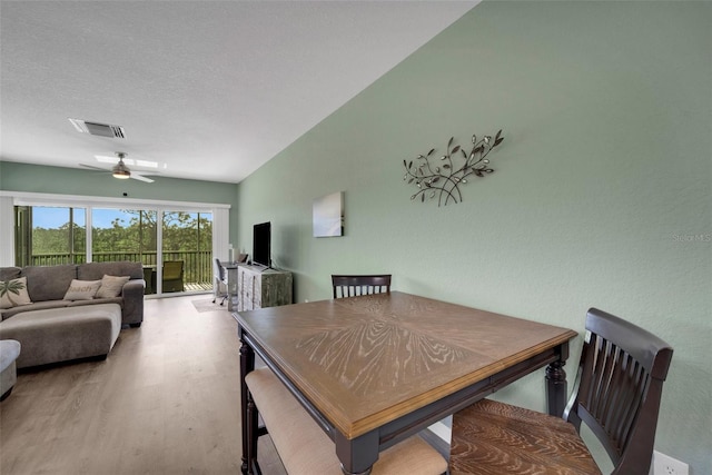 dining room with a textured ceiling, hardwood / wood-style flooring, ceiling fan, and vaulted ceiling