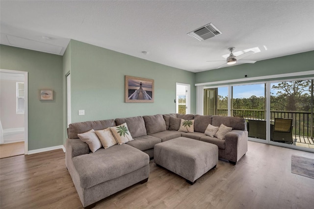 living room with light hardwood / wood-style flooring, a textured ceiling, and ceiling fan