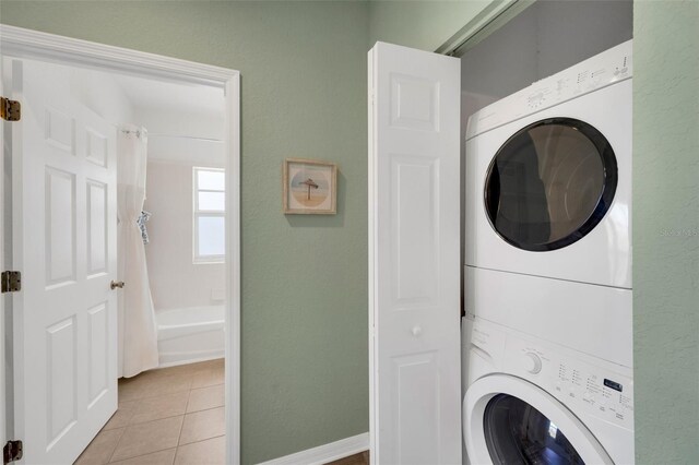 washroom with stacked washer / drying machine and light tile patterned flooring