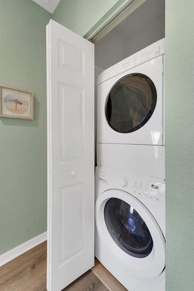 laundry area featuring stacked washing maching and dryer and hardwood / wood-style flooring