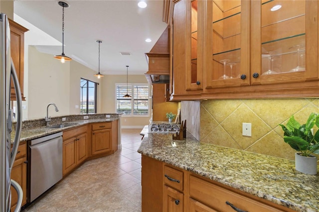 kitchen with sink, appliances with stainless steel finishes, tasteful backsplash, light stone countertops, and hanging light fixtures