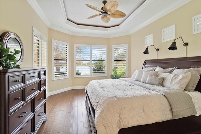 bedroom featuring ceiling fan, a tray ceiling, dark hardwood / wood-style flooring, and ornamental molding