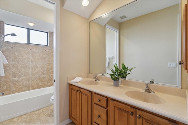 full bathroom with tile patterned floors, toilet, vaulted ceiling, tiled shower / bath combo, and vanity