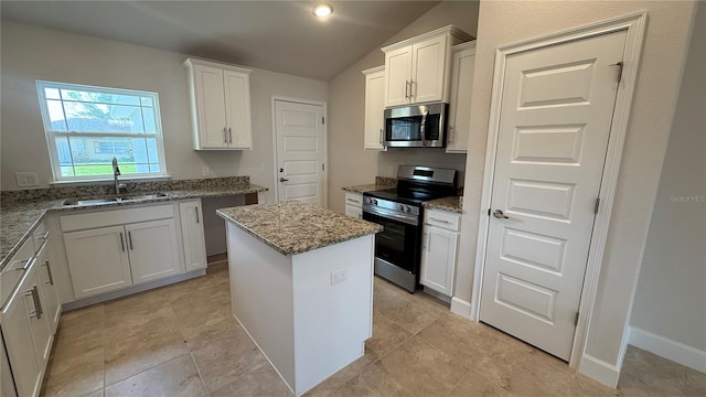 kitchen with lofted ceiling, white cabinets, appliances with stainless steel finishes, sink, and a center island