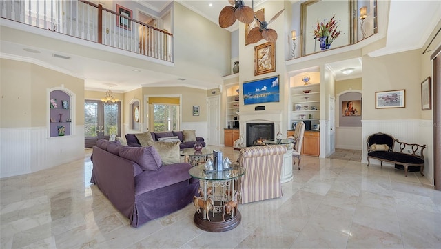 living room with ornamental molding, a high ceiling, and built in shelves