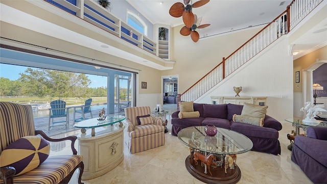 living room with decorative columns, ceiling fan, ornamental molding, and a high ceiling