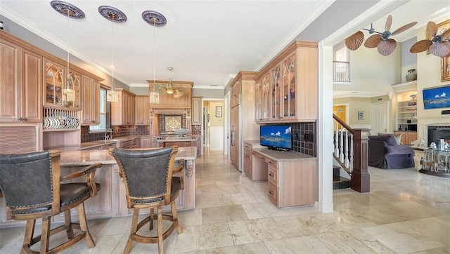 kitchen featuring hanging light fixtures, backsplash, ornamental molding, a kitchen bar, and stone counters