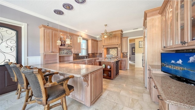 kitchen featuring kitchen peninsula, hanging light fixtures, a breakfast bar area, ornamental molding, and light stone counters