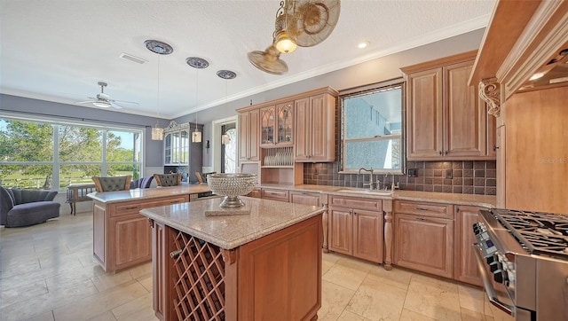 kitchen with sink, a kitchen island, backsplash, high end stainless steel range, and decorative light fixtures