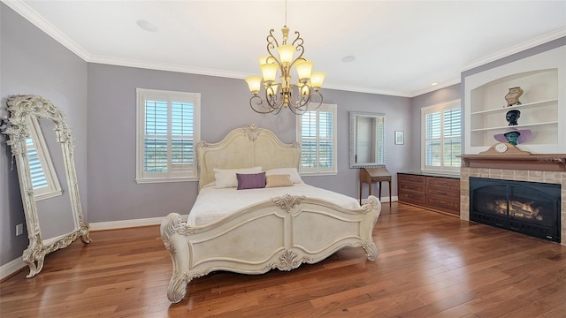 bedroom with ornamental molding, a notable chandelier, a tiled fireplace, and hardwood / wood-style flooring