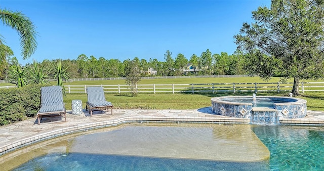 view of pool featuring a patio, pool water feature, a yard, and a rural view