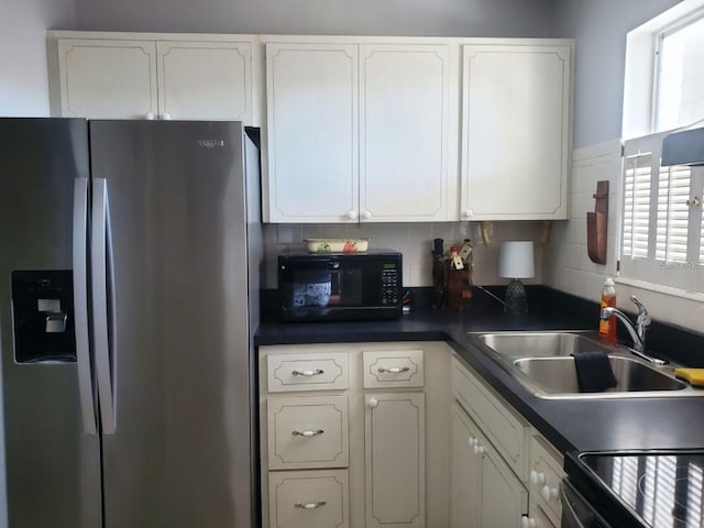 kitchen featuring sink, stainless steel fridge, white cabinetry, and decorative backsplash