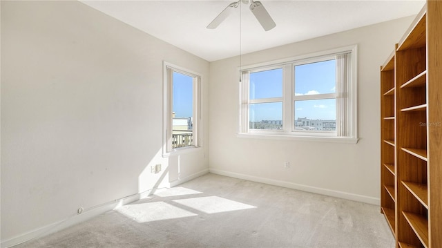 spare room with light carpet, plenty of natural light, and ceiling fan