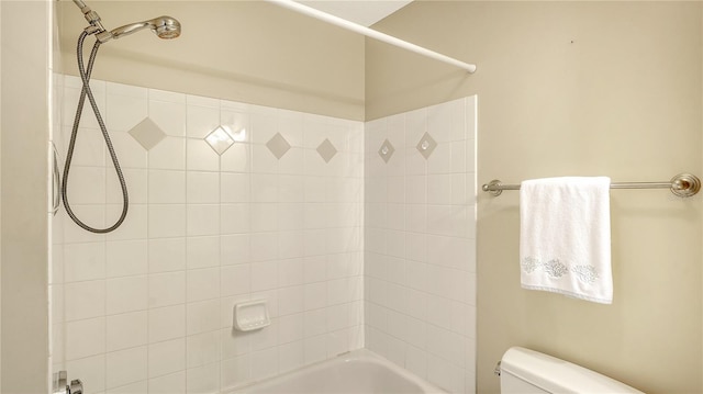 bathroom with tiled shower / bath combo and toilet