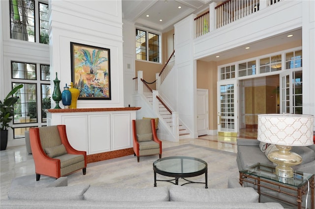 living room with crown molding, a towering ceiling, and a wealth of natural light