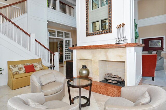 living room featuring a towering ceiling, a fireplace, and light tile patterned floors