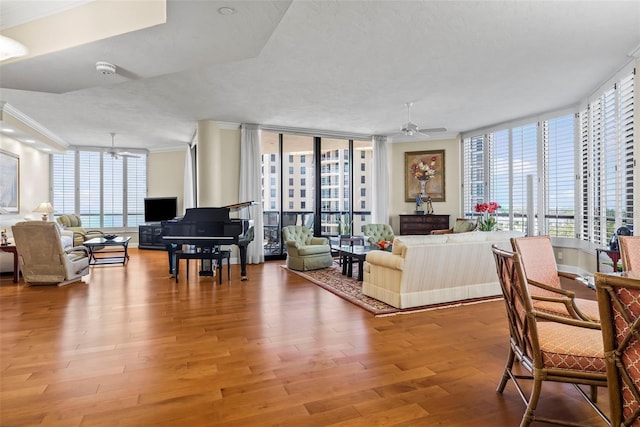 living room featuring wood-type flooring, plenty of natural light, and crown molding