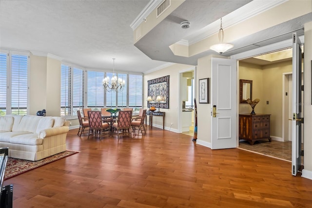 dining area featuring hardwood / wood-style flooring, ornamental molding, an inviting chandelier, and a textured ceiling