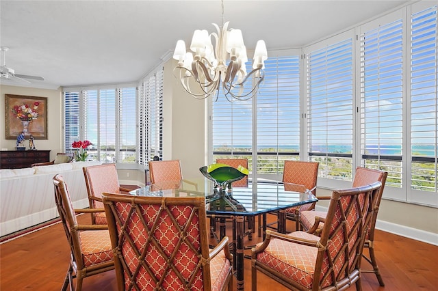 dining room featuring hardwood / wood-style flooring, plenty of natural light, ceiling fan with notable chandelier, and a water view