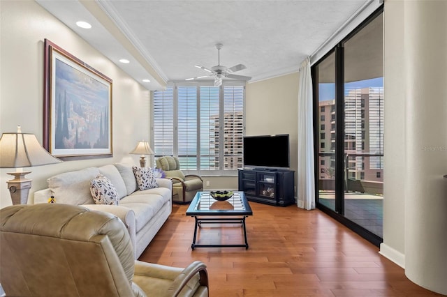 living room featuring hardwood / wood-style flooring, ornamental molding, and ceiling fan