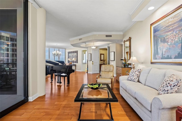 living room featuring crown molding, a chandelier, and light wood-type flooring