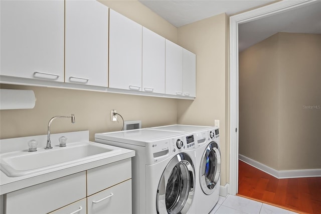 laundry room with cabinets, sink, washer and dryer, and light tile patterned floors