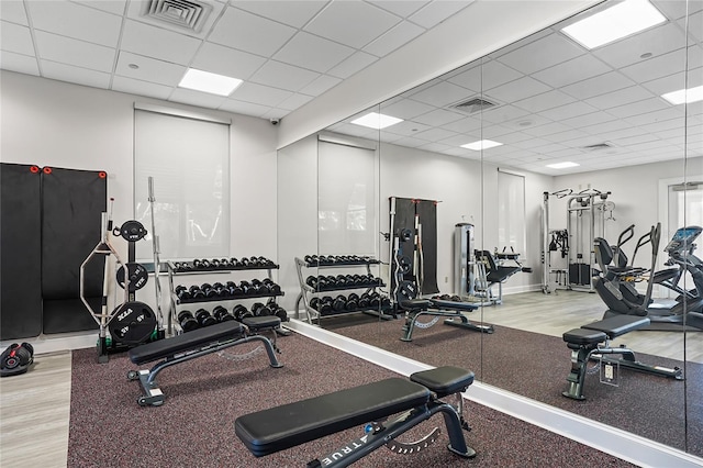 exercise room featuring light wood-type flooring and a drop ceiling