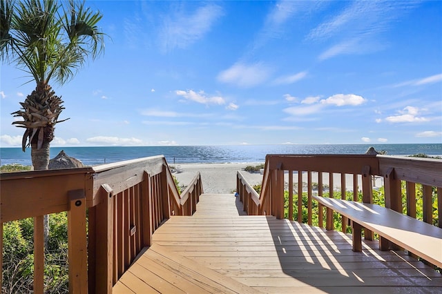 surrounding community featuring a deck with water view and a beach view