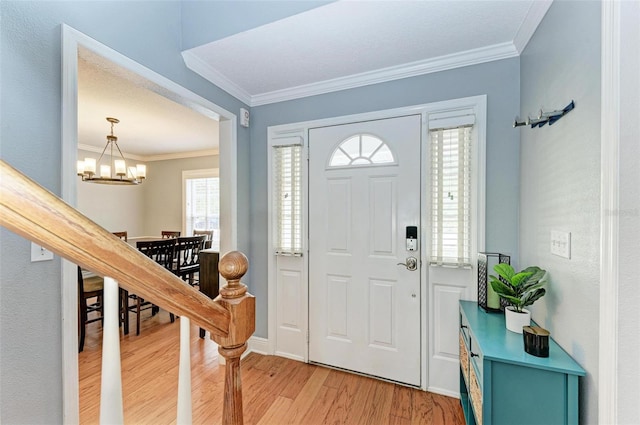 entryway featuring light hardwood / wood-style floors, crown molding, and a chandelier