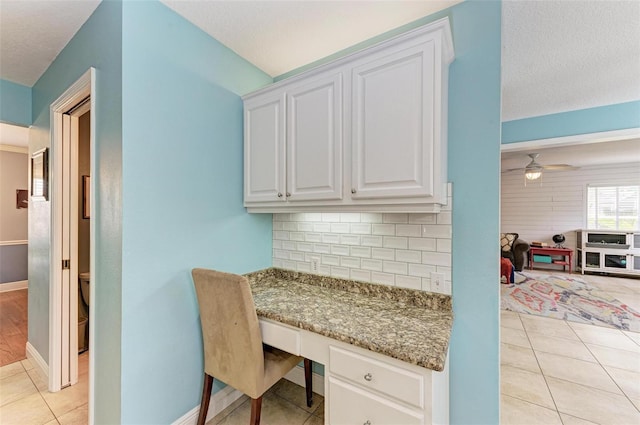 office with built in desk, ceiling fan, a textured ceiling, and light tile patterned floors