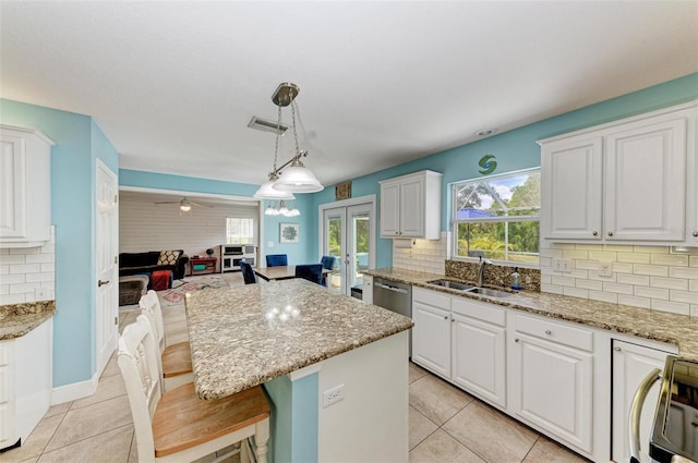 kitchen with white cabinets, a kitchen island, a kitchen bar, decorative light fixtures, and sink