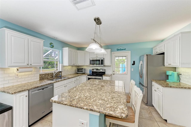 kitchen featuring sink, a center island, white cabinetry, stainless steel appliances, and pendant lighting