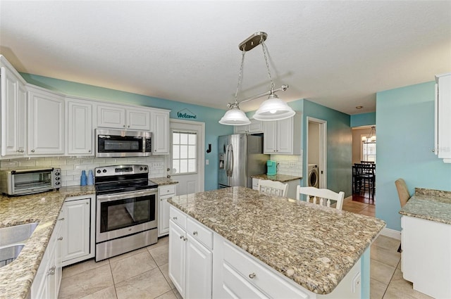 kitchen with white cabinetry, stainless steel appliances, decorative light fixtures, and a kitchen island