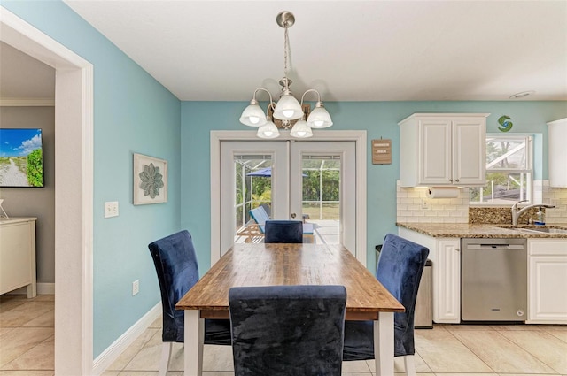 tiled dining space with french doors, a chandelier, sink, and crown molding