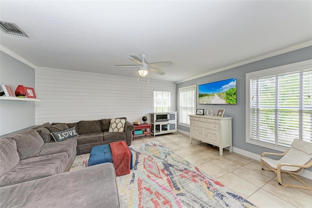 living room with a wealth of natural light, crown molding, light tile patterned flooring, and ceiling fan