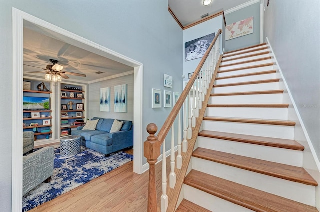 stairway featuring crown molding, hardwood / wood-style flooring, and ceiling fan