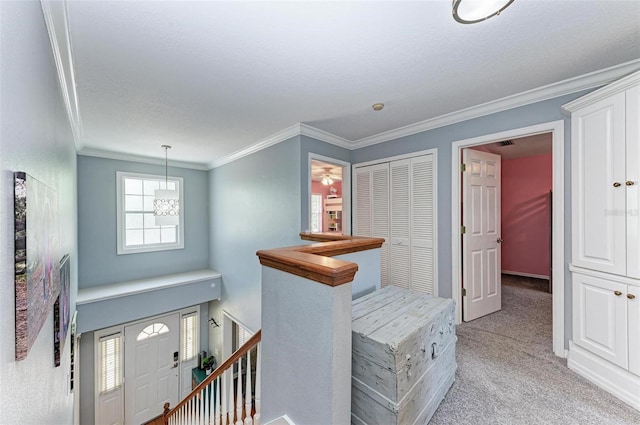 hallway featuring ornamental molding, a textured ceiling, and light colored carpet