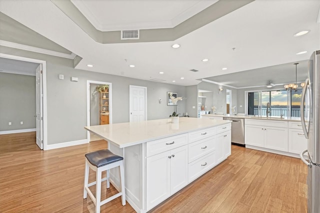 kitchen with white cabinets, a center island, light wood-type flooring, and crown molding