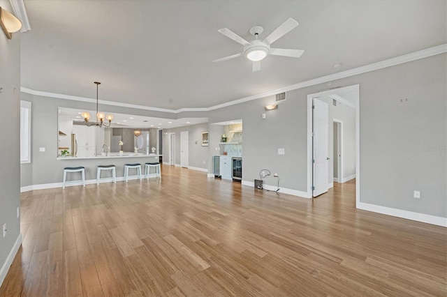 unfurnished living room featuring ceiling fan with notable chandelier, wine cooler, light hardwood / wood-style flooring, and crown molding