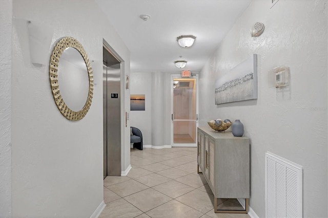 hall with light tile patterned floors and elevator